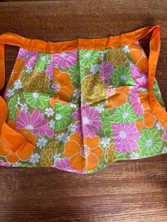 an orange and pink flowered purse sitting on top of a wooden table