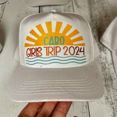 a white cap with the words, cabo girls trip 2021 printed on it is held up by someone's hand