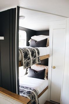 bunk beds in a small room with black walls and white bedding, along with pillows