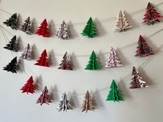 paper christmas trees are hung on a string in the shape of garlands, with red and green tinsel hanging from them