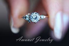 a woman's hand holding an engagement ring with blue stones