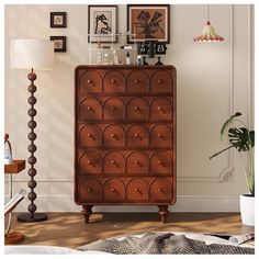 a brown dresser sitting on top of a wooden floor next to a lamp and pictures