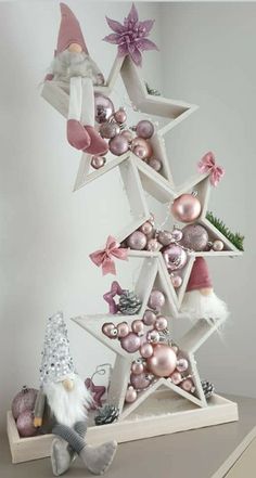 an ornament christmas tree with pink ornaments and santa clause hat on the top