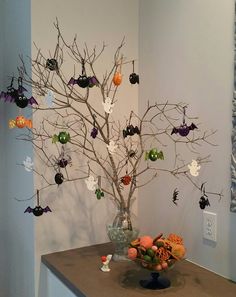 a tree with halloween decorations hanging from it's branches in a vase on top of a counter