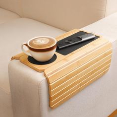 a cup of coffee sitting on top of a wooden tray next to a remote control