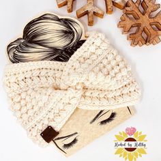 a knitted headband next to two wooden snowflakes and one with long hair