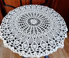 a white crocheted doily sitting on top of a wooden table next to a chair