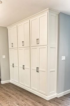 an empty room with white cupboards and wood flooring in the middle of it