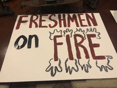 a sign that says, freshmen on fire with black and red writing underneath it