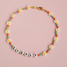 Colourful name necklace with beaded flowers. Made using beautiful Czech glass seed beads, black and white letter beads, strong, waxed jewellery cord and gold plated adjustable clasp closure. Fun everyday accessory for big and small. Necklace should not come into contact with water, chemicals or perfume.Please also take off while showering or swimming. Handmade with love by CharmedByEverly. Please note: this necklace contains small parts, to be used under adult supervision. Cheap Summer Letter Beads Necklaces, Name Beaded Necklace, Trendy Flower Shaped Jewelry With Letter Beads, Trendy Flower Shaped Letter Beads Jewelry, Trendy Flower-shaped Jewelry With Letter Beads, Trendy Flower-shaped Letter Beads Jewelry, Flower Necklace Diy, Beads Black And White, Flower Bead Necklace