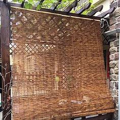 an outdoor area with a wooden bench and wicker covering the back of it's seat