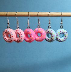 four donuts are hanging from a wooden bar with hooks on it and sprinkles all over them