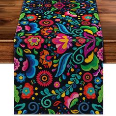 an image of a table runner with colorful flowers and leaves on black fabric, ready to be used as a centerpiece