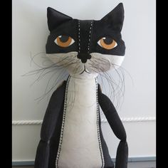 a black and white cat stuffed animal sitting next to a wall