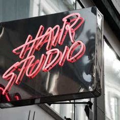 a neon sign that reads hair studio