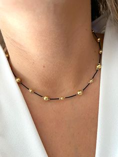 This handmade necklace features gold filled beads strung on black nylon thread, and is adjustable. Adjustable Choker Necklace With Gold Beads, Adjustable Gold Bead Choker Necklace, Elegant Black Necklace With Adjustable Cord, Adjustable Gold Beads Choker Necklace, Adjustable Gold Choker With Cord, Gold Choker With Adjustable Cord, Adjustable Gold Beads Choker, Adjustable Gold Choker With Round Beads, Adjustable Gold Choker