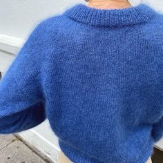 the back of a woman's blue sweater, with her hand on her hip