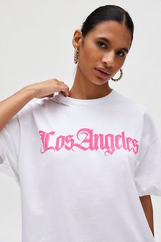 T-shirt dress featuring a Los Angeles destination graphic across the chest. Perfect as an oversized graphic tee or mini dress! Find it only at Urban Outfitters. Features Los Angeles Destination graphic t-shirt dress Oversized graphic tee Soft and stretchy jersey knit Crew neckline with drop shoulders and short sleeves Los Angeles graphic across the front Relaxed, slouchy fit Tunic length Easy pull-over style UO exclusive Content + Care 100% Cotton Machine wash Imported Size + Fit Model in White is 5’9.5" and wearing size S/M Measurements taken from size S/M Chest: 46" Length: 30.5" | Los Angeles Destination T-Shirt Dress in White, Women's at Urban Outfitters Los Angeles Graphic, Women's Graphic Tees, Vintage Graphic Tees, Los Angeles Shopping, Fitted Tunic, Urban Outfitters Women, Oversized Graphic Tee, Graphic Tees Vintage, Vintage Graphic