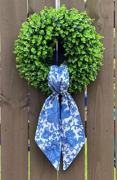 a blue and white bow tied to a wooden fence with a green wreath on it