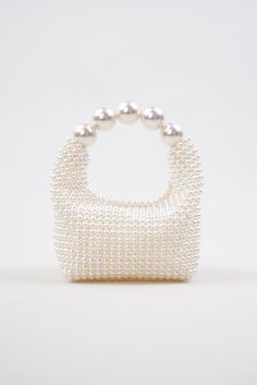 Introducing the stunning Nuit Blanche Pearl Bag by Vanina, a true embodiment of luxury and sophistication. Impossibly chic, this exquisite bag is a true masterpiece of artistry and craftsmanship that will become a wedding piece you will cherish for years to come. This bag boasts a radiant, iridescent white hue that shimmers and sparkles in the light, adding an ethereal and enchanting touch to your ensemble. Each pearl has been meticulously hand-sewn onto the bag, creating a seamless, flawless finish that exudes elegance and refinement. All of Vanina's pieces are handcrafted by skilled artisans in Lebanon, using ethically sourced and sustainable materials, making it an environmentally conscious choice you can feel good about. White All-over faux pearl embellishments Curved beaded top handle Hand Beaded Bag, Elegant Style Women, Iridescent White, Pearl Bag, Handmade Jewelry Tutorials, Beaded Top, Leather Pieces, Beaded Bags, Acrylic Beads