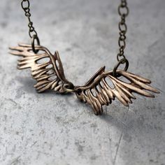 a close up of a metal object on a chain with wings hanging from it's sides