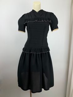 Cute 1940'S black rayon dress with a fitted bodice and a drop waist. There is this pleated flouncy trim that lines the chest and wraps around the drop waist. There is an attached belt that ties in the back. Super sweet. The sleeves are short and puffy. There is a metal talon side zipper as well as 4 cloth covered buttons in back along the neckline. The skirt is rather short and flirty, which reminds me of cute baby doll dresses. This dress is in EXCELLENT VINTAGE CONDITION... no real issues to p 1950s Fitted Vintage Dress For Work, Fitted 1950s Vintage Dress For Work, Fitted Vintage 1950s Dress For Workwear, 1950s Vintage Dress For Work, 1950s Style Fitted Vintage Dress For Work, Classic Fitted Vintage Dress For Vintage Events, Black Victorian Dress With Fitted Bodice, Fitted Black Dress With Pleated Waist, Black Fitted Dress With Pleated Waist