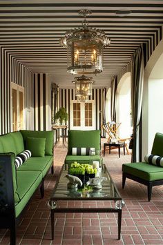 a living room with green couches and black and white stripes on the wall behind them