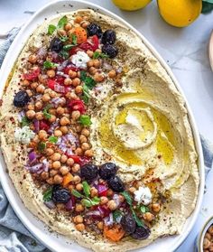 hummus with olives, red onions and other ingredients on a white platter