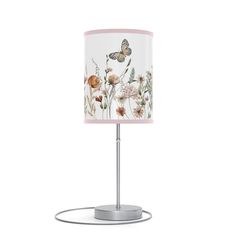 a table lamp with a white and yellow shade on the base, decorated with wildflowers