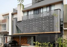 a car is parked in front of a modern house with an intricate design on the side