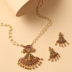 Description: Introducing the Padmika Antique Pendant Set - a stunningly crafted piece of jewelry. Featuring antique pearl beads tassel studded with colorful kempu stones in the form of a fish, a peacock, and other motifs, this timeless set is perfect for special occasions. Details & Specifications: Materials used: CZ stones with Antique Gold Plating Weight - Pendant 22, Earring 12.5 gm Length - Pendant 7, Earring 4, Chain 23 cm Make it custom Want to make it a custom pendant? Sure! Reach out to Traditional Festive Jewelry Set With Pearl Pendant, Festive Traditional Jewelry Set With Pearl Pendant, Traditional Pearl Pendant Jewelry Set For Celebration, Traditional Temple Necklace With Pearl Drop For Festive, Traditional Temple Necklace With Pearl Pendant For Festive Occasions, Festive Traditional Temple Necklace With Pearl Pendant, Traditional Pearl Necklace With Dangling Beads As A Gift, Traditional Kundan Necklace With Dangling Beads, Elegant Multicolor Temple Necklace With Latkans