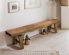 a wooden bench sitting in the corner of a room next to pictures on the wall