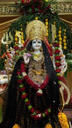 an idol is displayed in the middle of a room with flowers and garlands around it