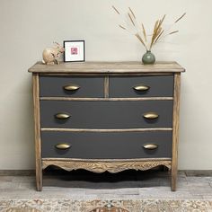 a grey dresser with gold handles and drawers on top of a rug next to a white wall