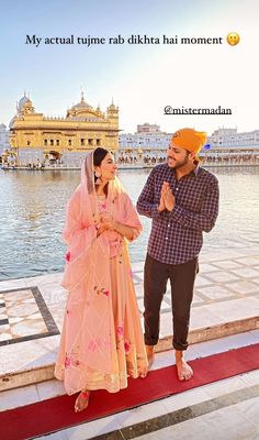 a man and woman standing next to each other in front of a body of water