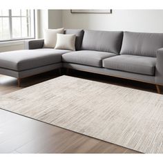 a living room scene with focus on the sectional sofa and rug in the foreground