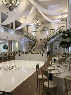 an elegant wedding reception with white draping and chandeliers on the ceiling