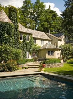 the house is surrounded by greenery and stone steps leading up to it's pool