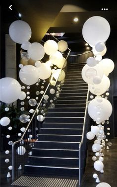 some white balloons are hanging down the stairs