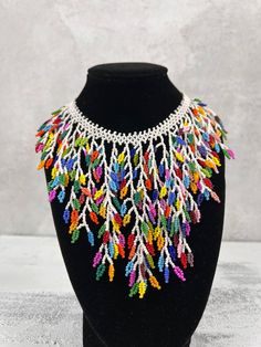 a black mannequin with multicolored beads and chains hanging from it's neck