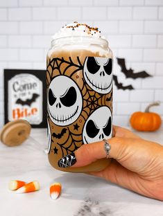 a hand holding up a drink with halloween decorations on it