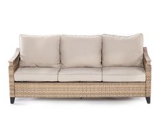 a wicker couch with four pillows on it's arm and backrests