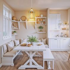 a white table and bench in a room with wooden floors, shelves on the wall