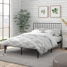 a bedroom with white brick walls and black metal bed frame in the corner, along with a plant