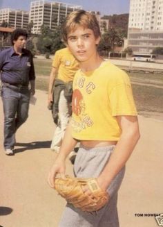 a young man holding a catchers mitt on top of a field