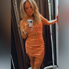 a woman in an orange dress taking a selfie