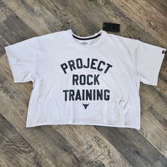 Under Armour Men's Project Rock Cut Off Crop Workout Shirt Size: 2xl Color: White/Black Writing Loose Fit Approximate Measurements: Chest: 26" Total Length: 22" Man Projects, Black Writing, Under Armour Shirts, Under Armour Men, Cut Off, Workout Shirts, Under Armour, White Black, Colorful Shirts