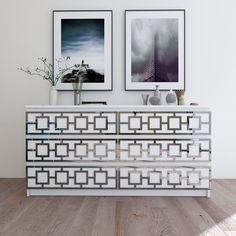 two framed pictures hang on the wall next to a white cabinet with an intricate design