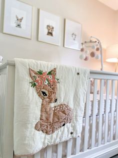 a baby crib with pictures on the wall and a deer blanket hanging from it