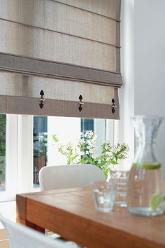 a dining room table with glasses and vases on it, next to a window